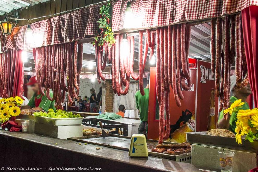 Imagem de uma barraca com linguiças penduradas na Festa de Quiririm.